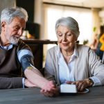 Happy senior couple measuring blood pressure at home. Disease prevention